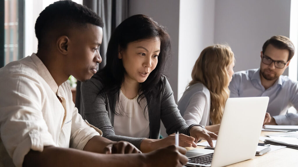 Group of coworkers discussing title services on laptops on a desk