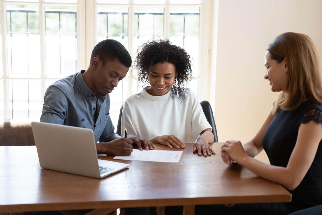 Couple signing title insurance documents in front of Quaint Oak Abstract employee