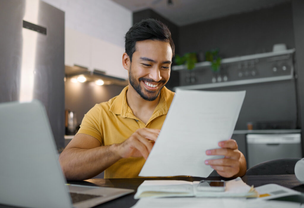 Man smiling holding title service documents in kitchen